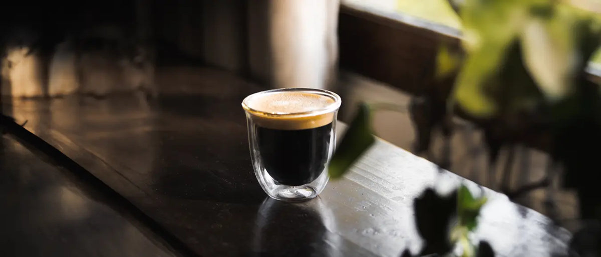 Ein frischer Espresso mit viel Crema auf einem dunklen Tisch