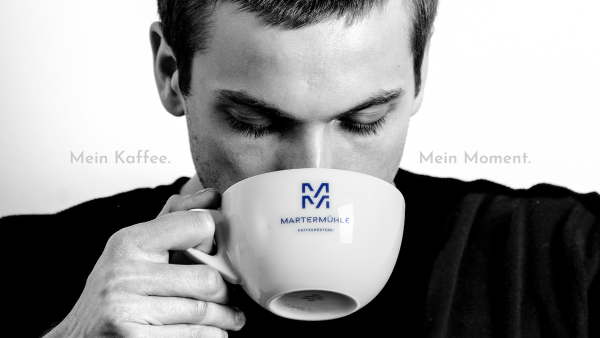 Junger Mann der einen Cappuccino aus einer Martermühle Tasse trinkt.