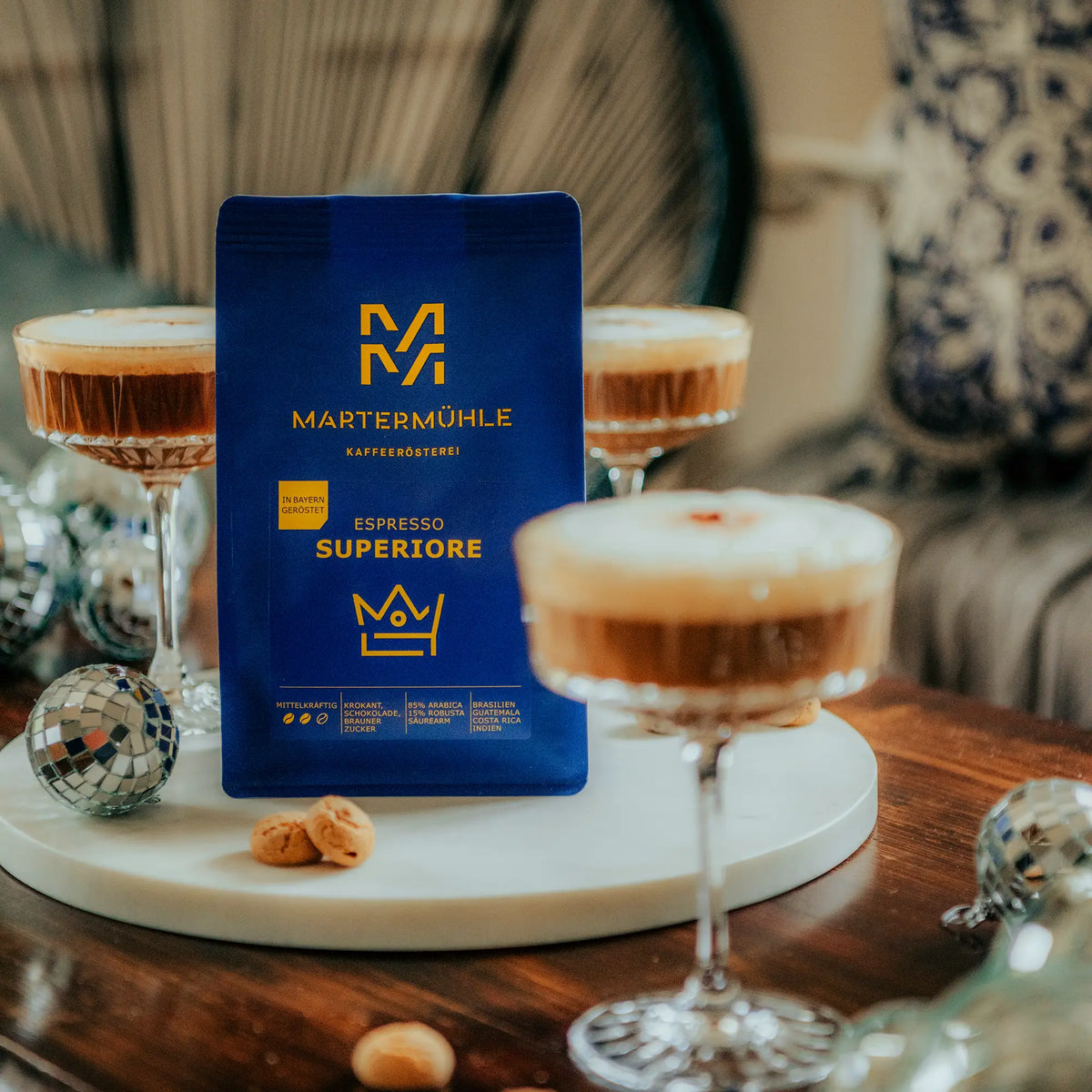 Eine Packung Espresso Superiore auf einem dekorierten Tisch mit Diskokugeln und Gläsern mit Espresso Martini.
